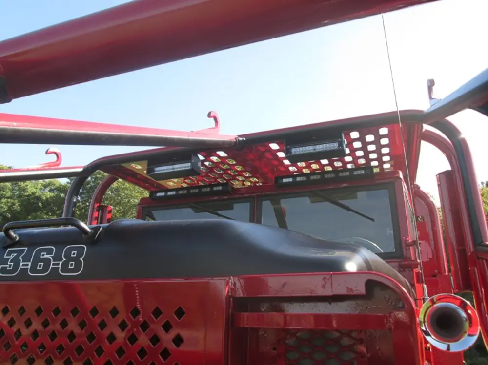 Exterior view of small fire truck showing cab, body compartments, and wheel/tire area.