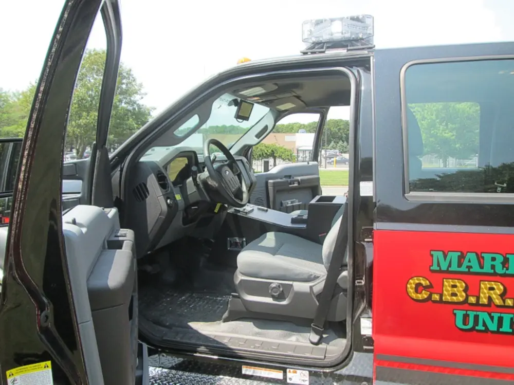 Exterior view of small fire truck showing cab, body compartments, and wheel/tire area.