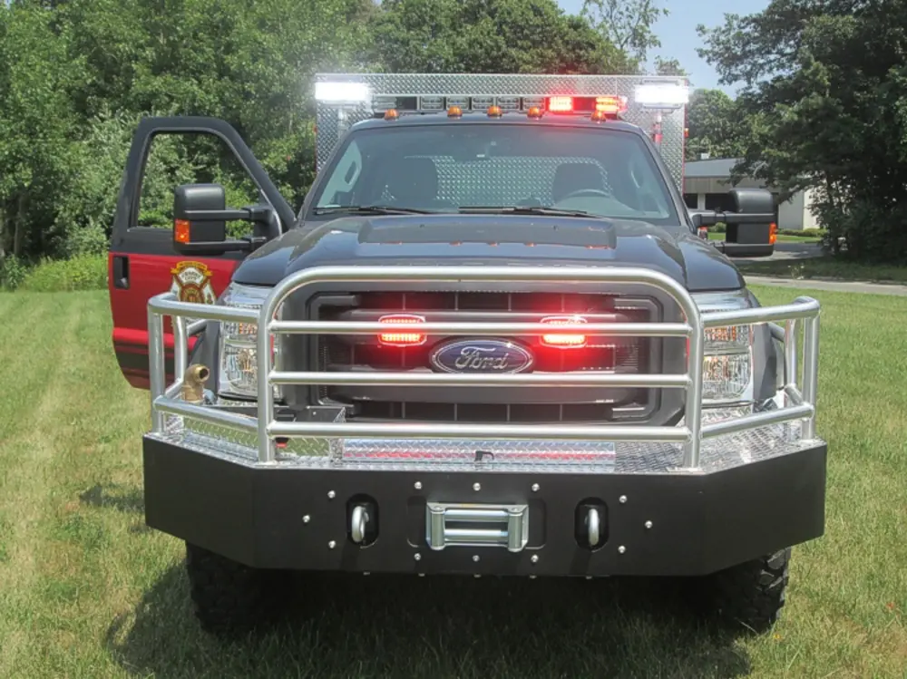 Exterior view of small fire truck showing cab, body compartments, and wheel/tire area.