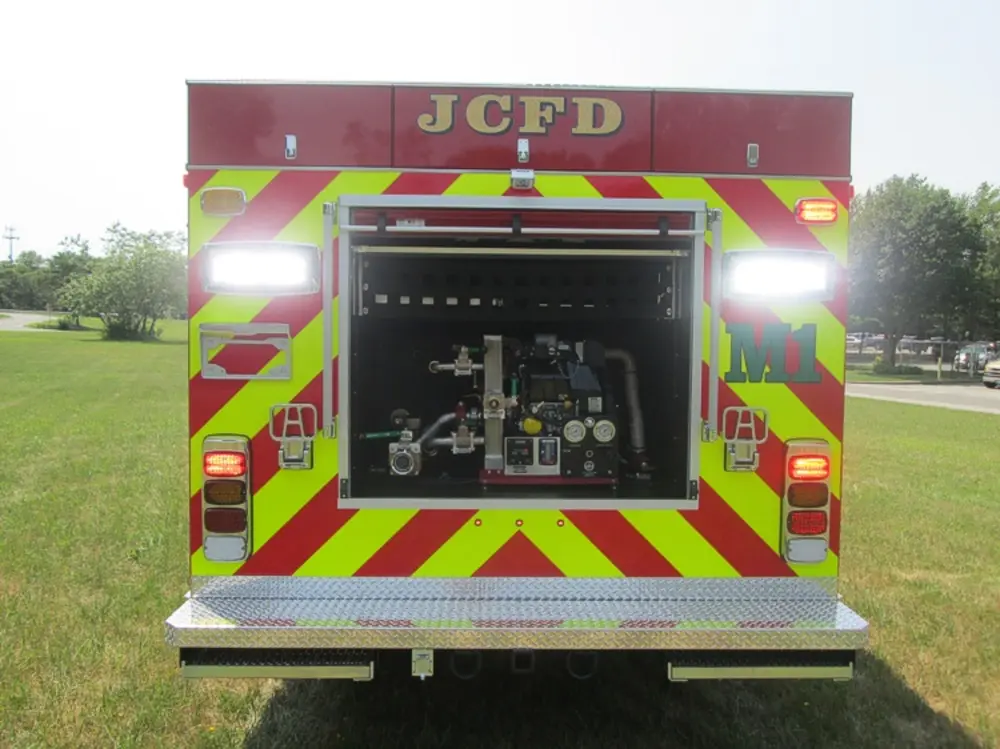 Exterior view of small fire truck showing cab, body compartments, and wheel/tire area.