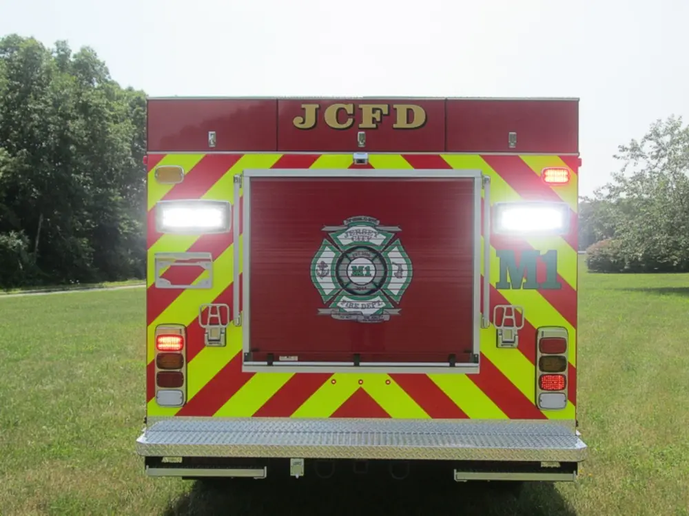 Exterior view of small fire truck showing cab, body compartments, and wheel/tire area.