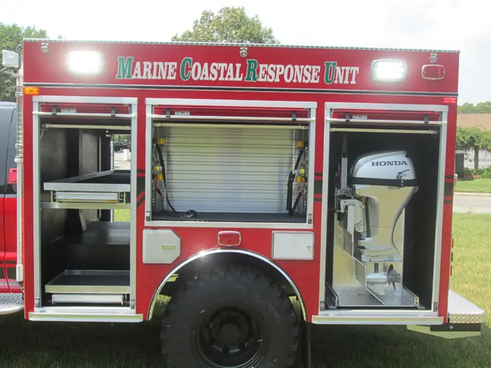 Exterior view of small fire truck showing cab, body compartments, and wheel/tire area.