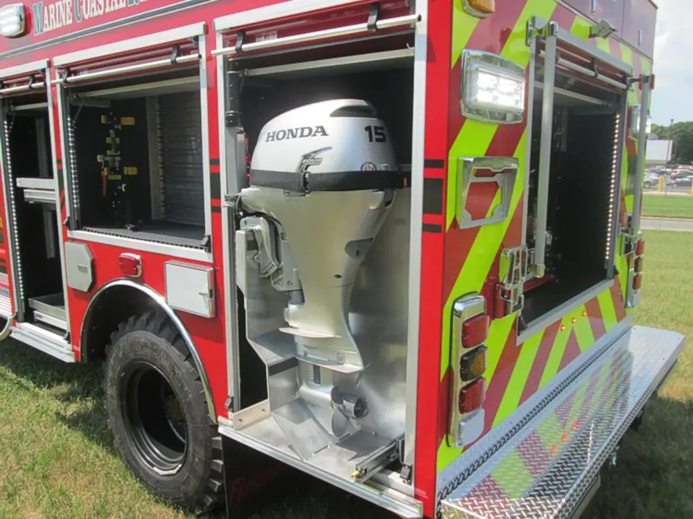 Exterior view of small fire truck showing cab, body compartments, and wheel/tire area.
