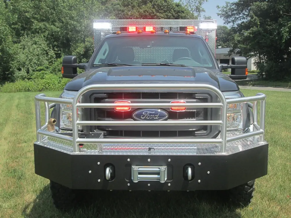 Exterior view of small fire truck showing cab, body compartments, and wheel/tire area.