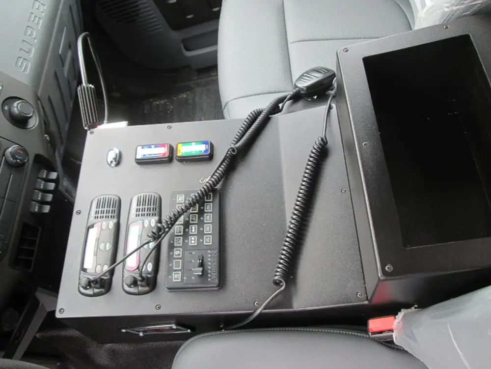 Exterior view of small fire truck showing cab, body compartments, and wheel/tire area.