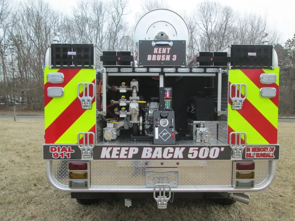 Exterior view of small fire truck showing cab, body compartments, and wheel/tire area.