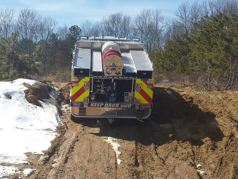 Exterior view of small fire truck showing cab, body compartments, and wheel/tire area.