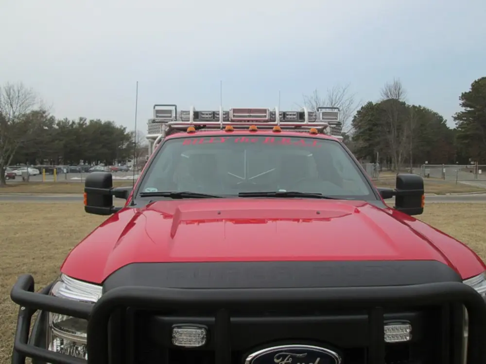 Exterior view of small fire truck showing cab, body compartments, and wheel/tire area.