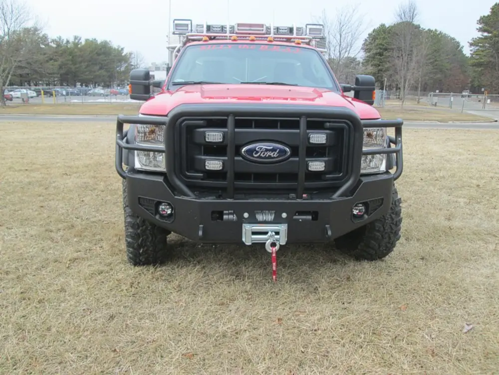 Exterior view of small fire truck showing cab, body compartments, and wheel/tire area.