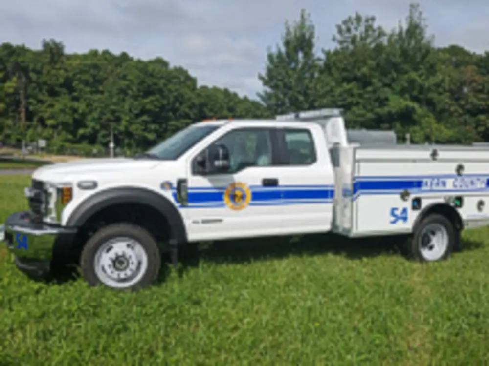 Exterior view of small fire truck showing cab, body compartments, and wheel/tire area.