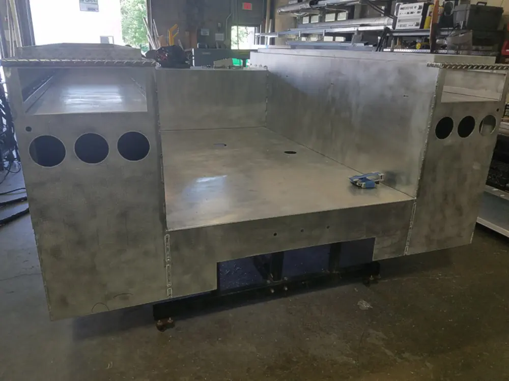 Exterior view of small fire truck showing cab, body compartments, and wheel/tire area.