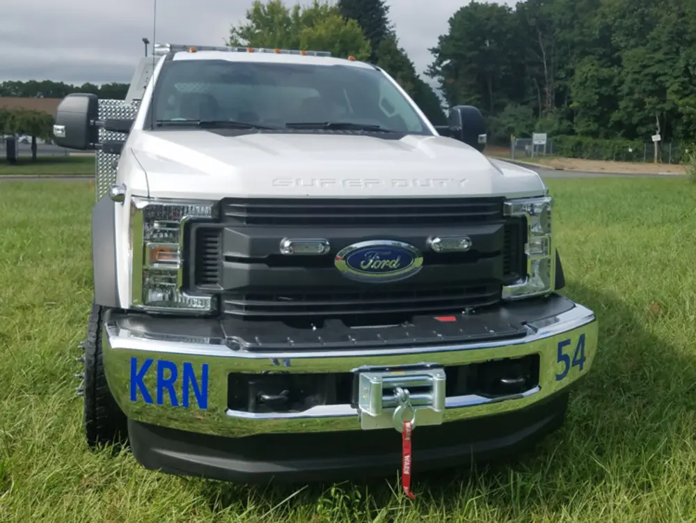 Exterior view of small fire truck showing cab, body compartments, and wheel/tire area.