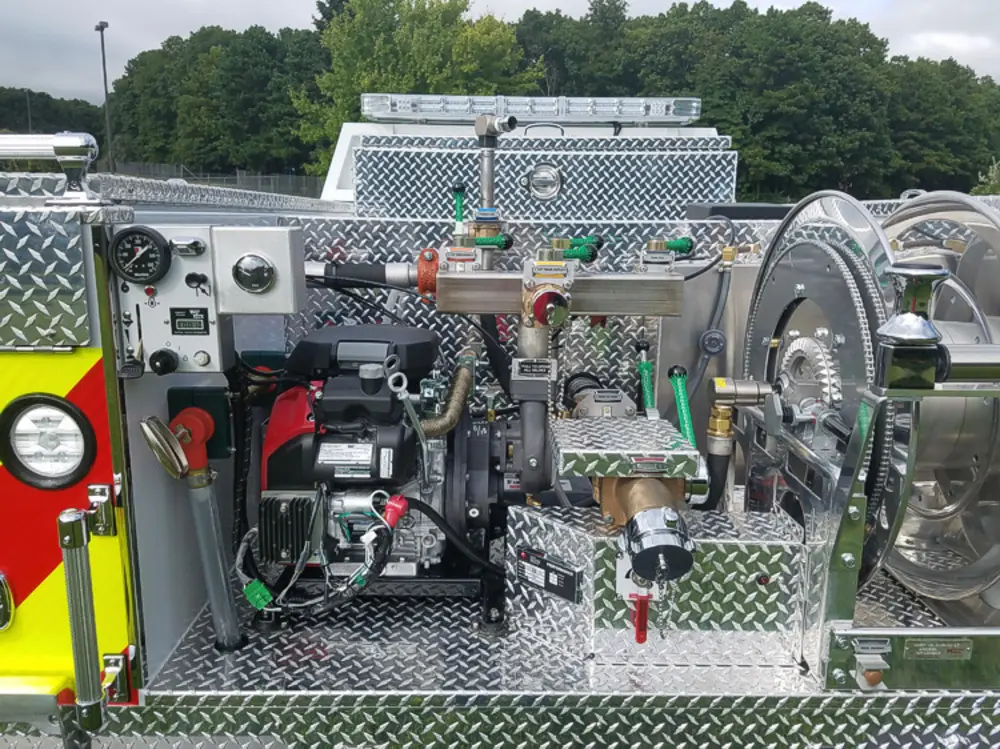 Exterior view of small fire truck showing cab, body compartments, and wheel/tire area.