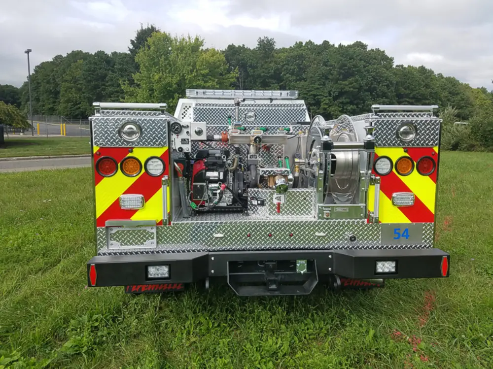 Exterior view of small fire truck showing cab, body compartments, and wheel/tire area.