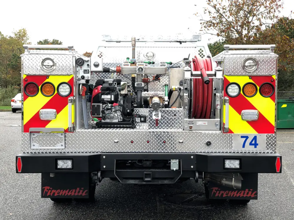 Exterior view of small fire truck showing cab, body compartments, and wheel/tire area.
