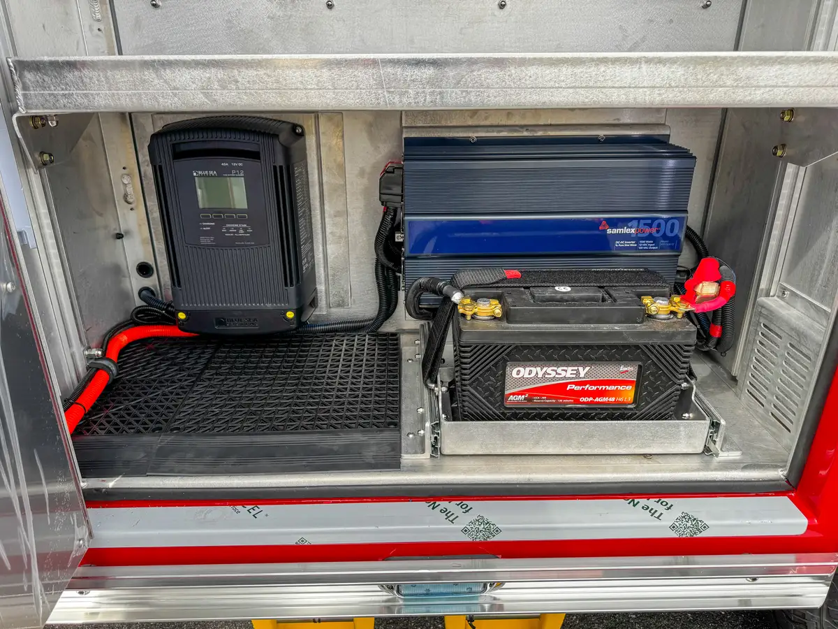 Compartment interior showing charger, battery, and cabling.