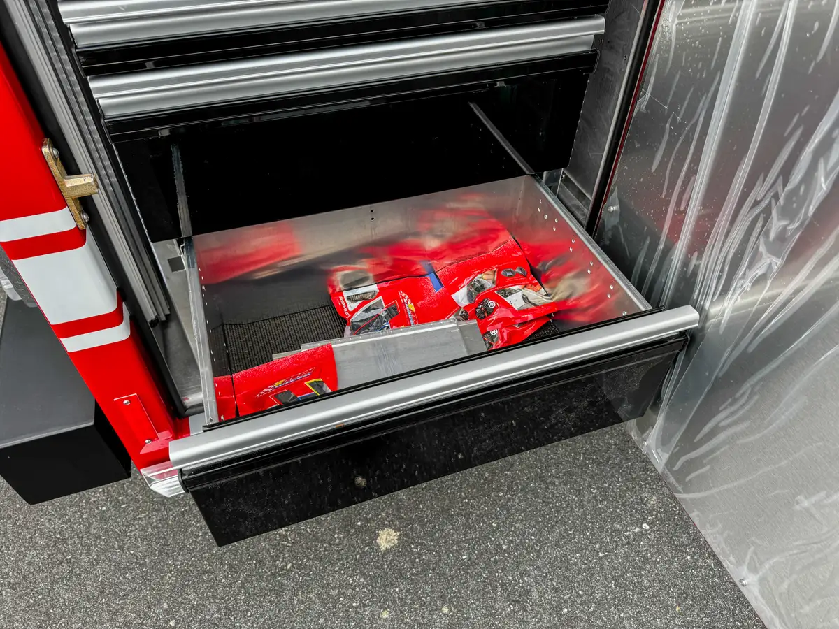 Pull-out compartment tray with red firefighting equipment inside.