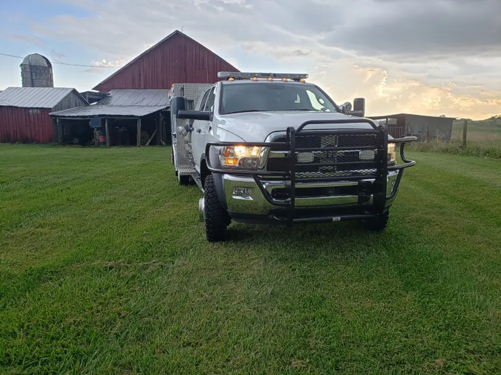 Exterior view of small fire truck showing cab, body compartments, and wheel/tire area.