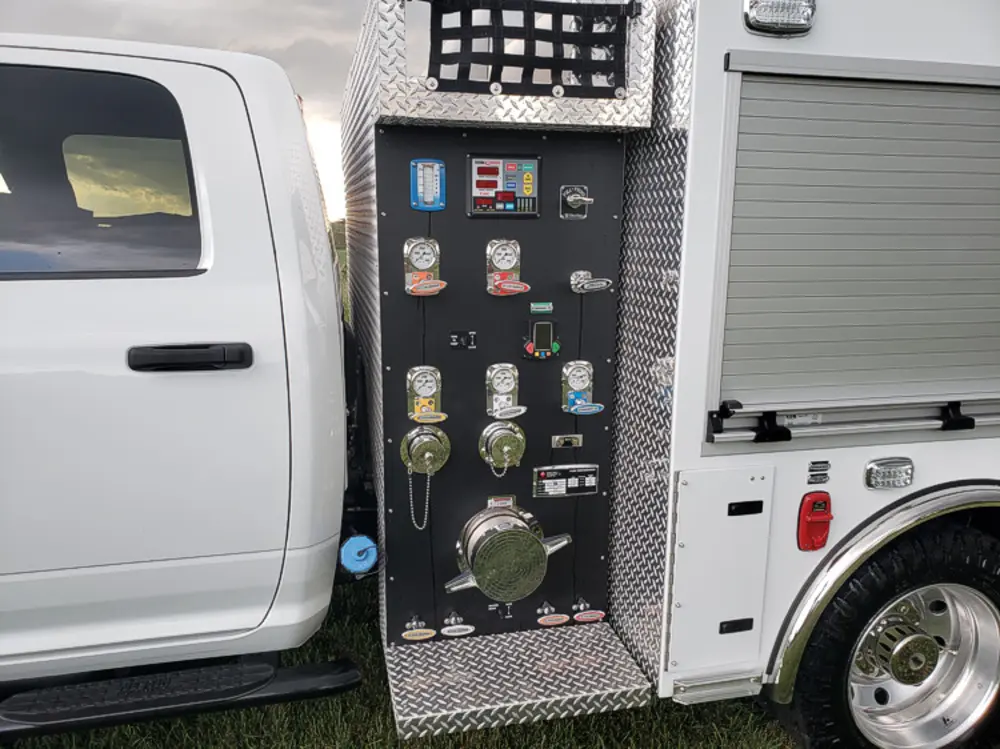 Exterior view of small fire truck showing cab, body compartments, and wheel/tire area.