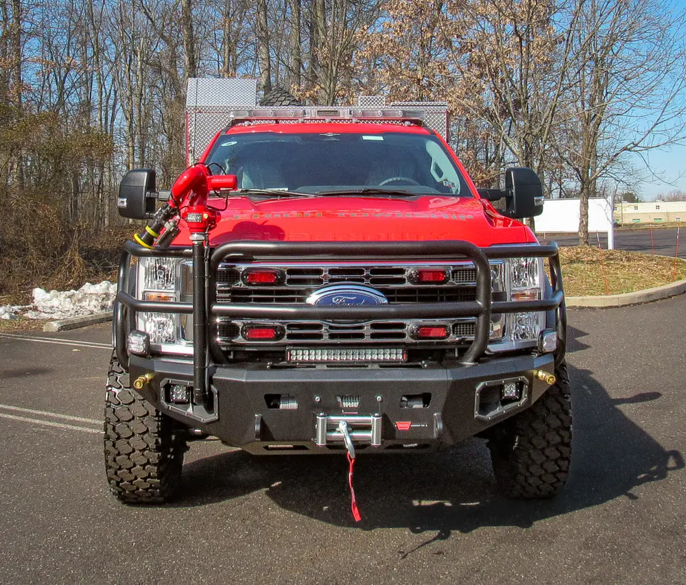 Exterior view of small fire truck showing cab, body compartments, and wheel/tire area.