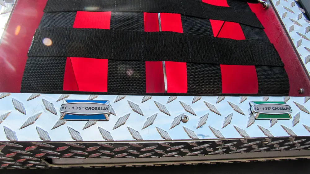 Exterior view of small fire truck showing cab, body compartments, and wheel/tire area.