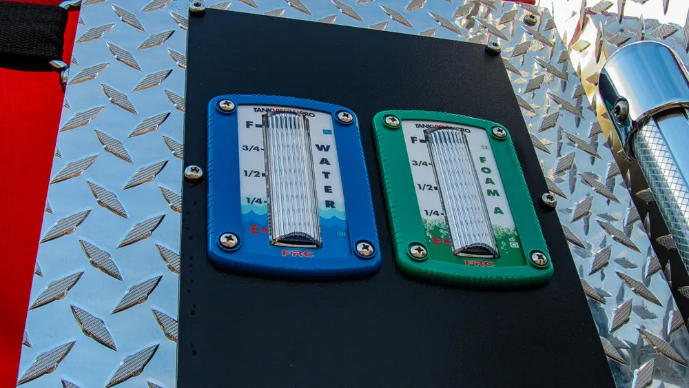 Exterior view of small fire truck showing cab, body compartments, and wheel/tire area.