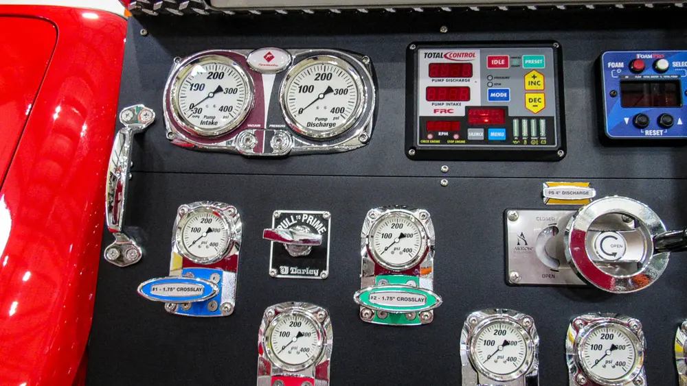 Exterior view of small fire truck showing cab, body compartments, and wheel/tire area.