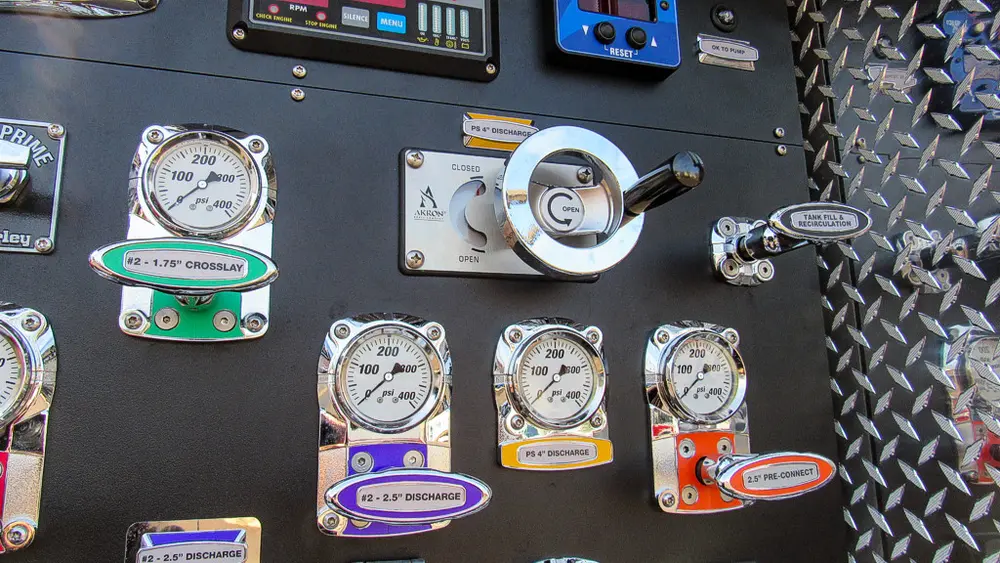 Exterior view of small fire truck showing cab, body compartments, and wheel/tire area.