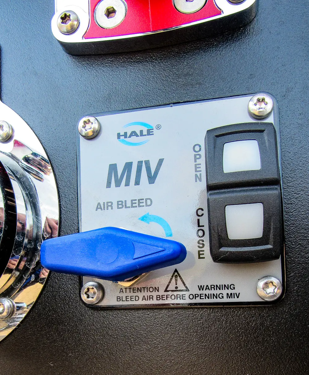 Exterior view of small fire truck showing cab, body compartments, and wheel/tire area.