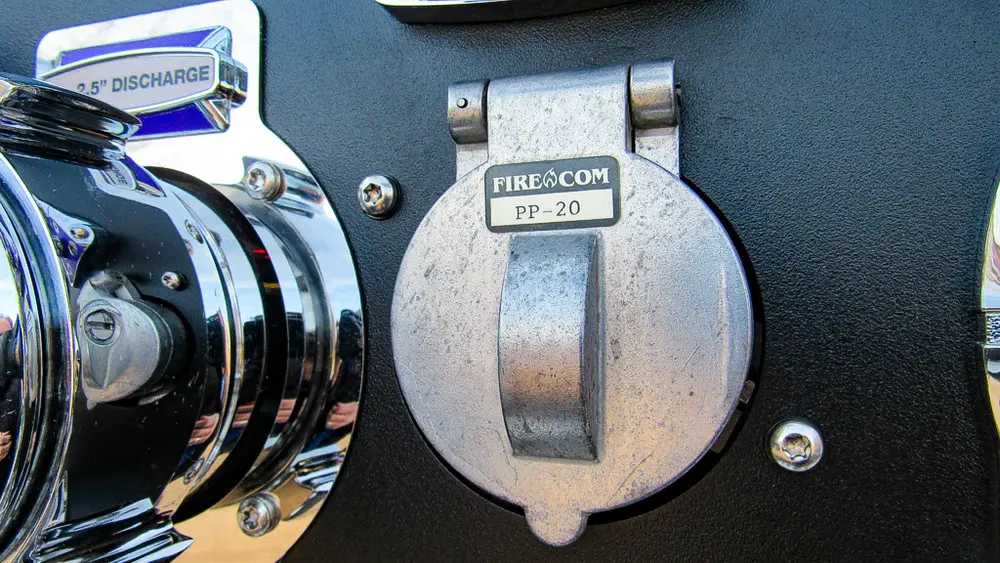 Exterior view of small fire truck showing cab, body compartments, and wheel/tire area.