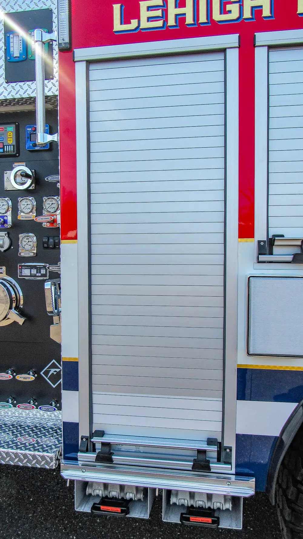 Exterior view of small fire truck showing cab, body compartments, and wheel/tire area.