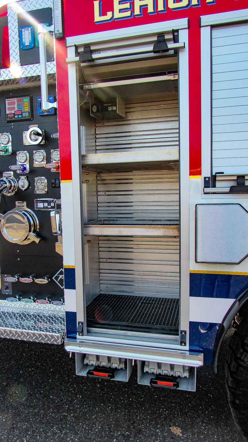 Exterior view of small fire truck showing cab, body compartments, and wheel/tire area.