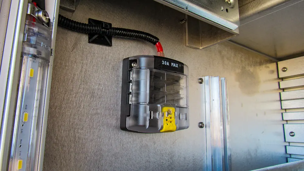 Exterior view of small fire truck showing cab, body compartments, and wheel/tire area.