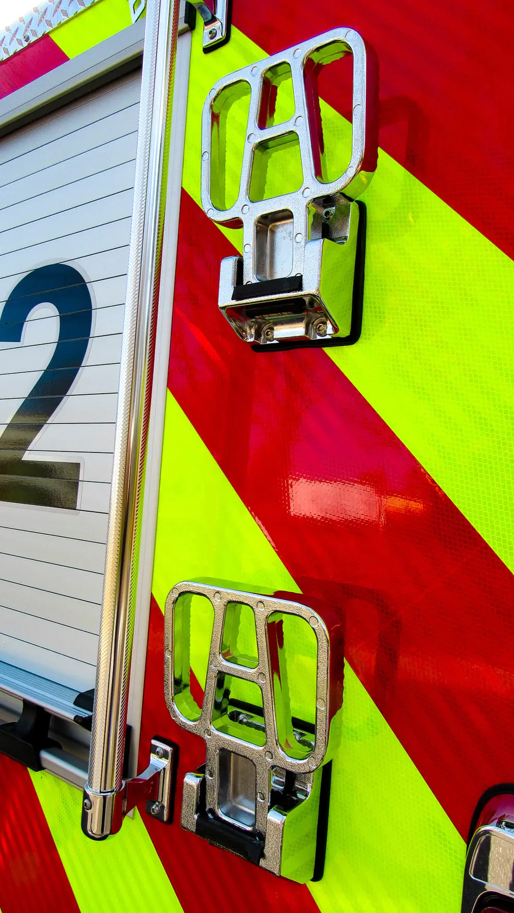 Exterior view of small fire truck showing cab, body compartments, and wheel/tire area.