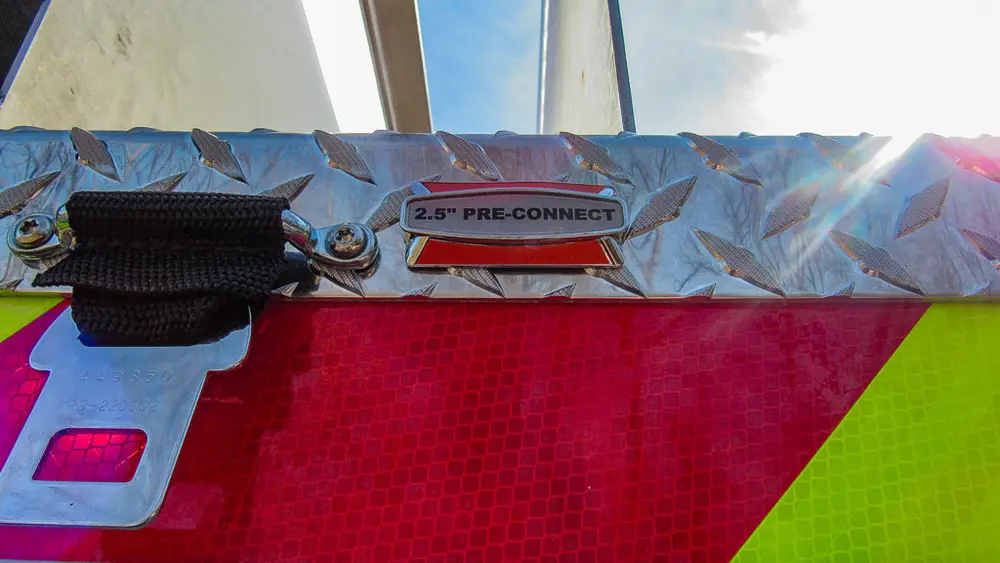 Exterior view of small fire truck showing cab, body compartments, and wheel/tire area.