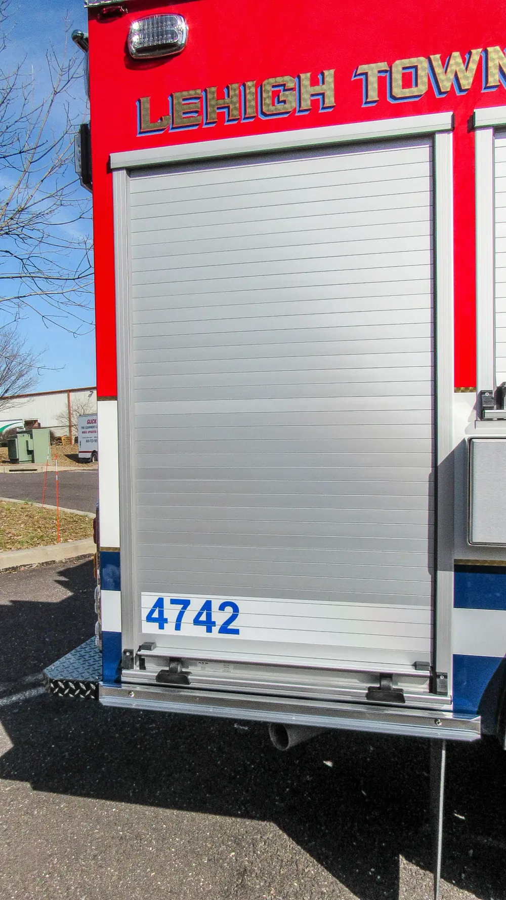 Exterior view of small fire truck showing cab, body compartments, and wheel/tire area.