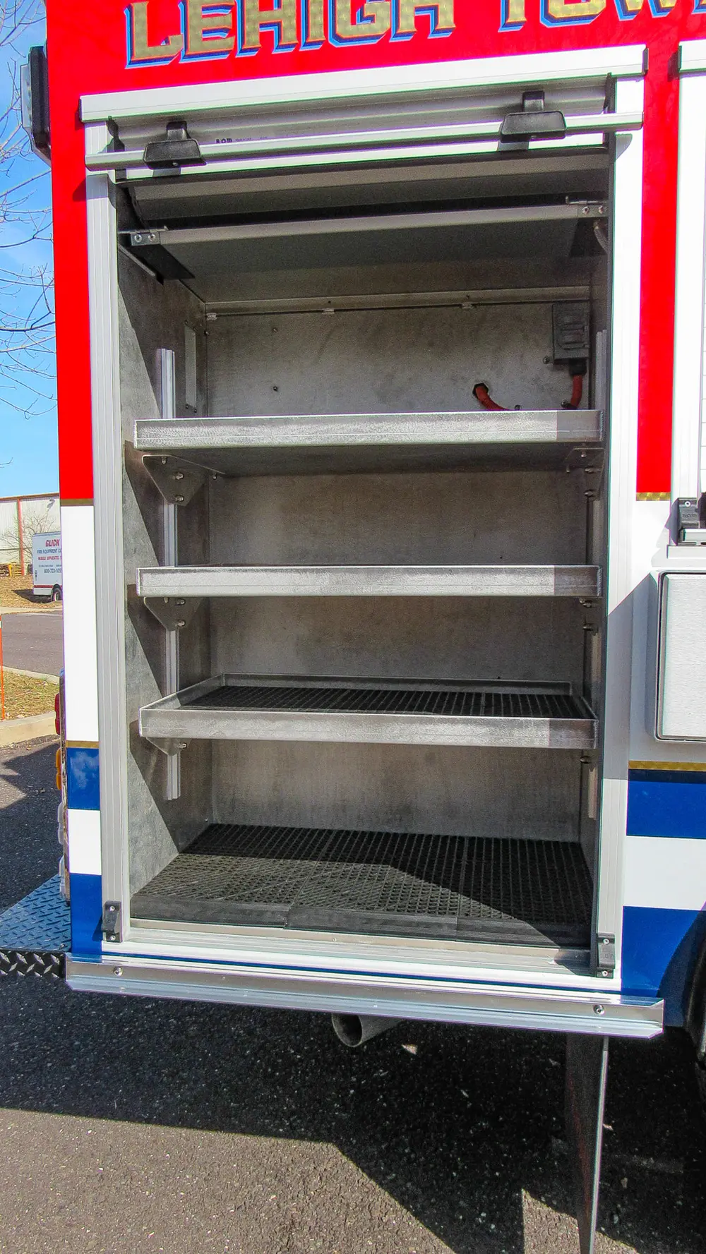 Exterior view of small fire truck showing cab, body compartments, and wheel/tire area.