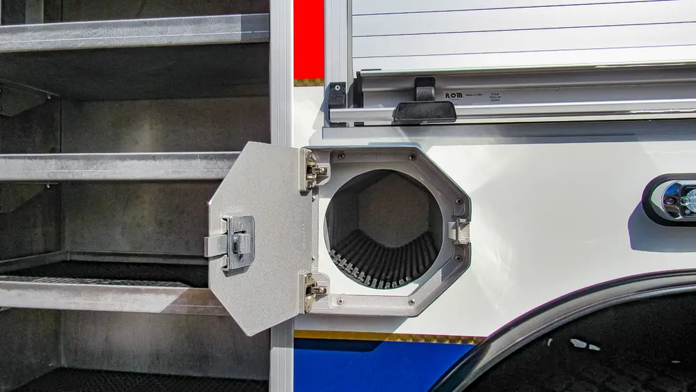 Exterior view of small fire truck showing cab, body compartments, and wheel/tire area.