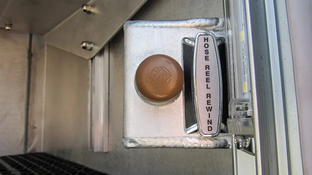 Exterior view of small fire truck showing cab, body compartments, and wheel/tire area.