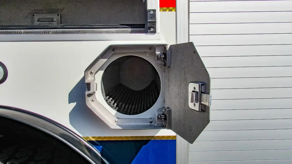 Exterior view of small fire truck showing cab, body compartments, and wheel/tire area.