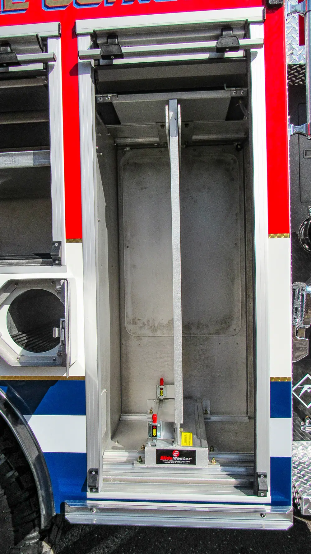 Exterior view of small fire truck showing cab, body compartments, and wheel/tire area.
