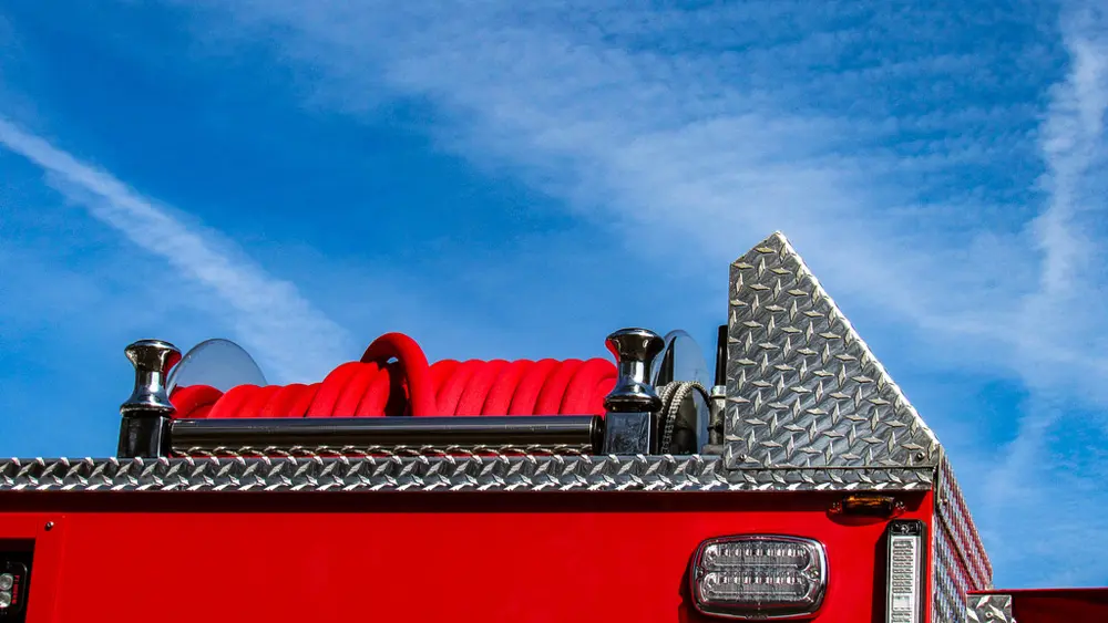 Exterior view of small fire truck showing cab, body compartments, and wheel/tire area.