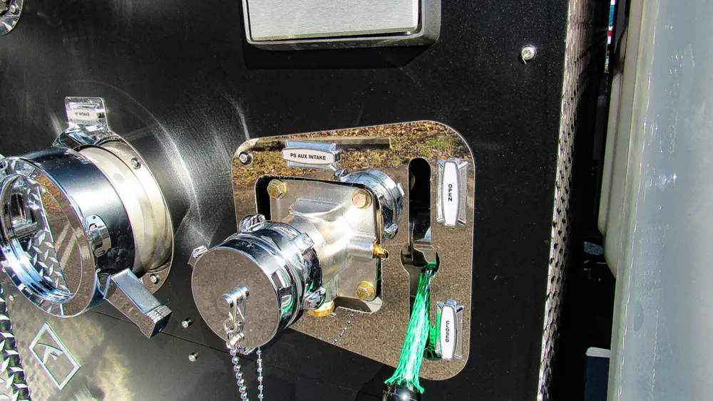 Exterior view of small fire truck showing cab, body compartments, and wheel/tire area.