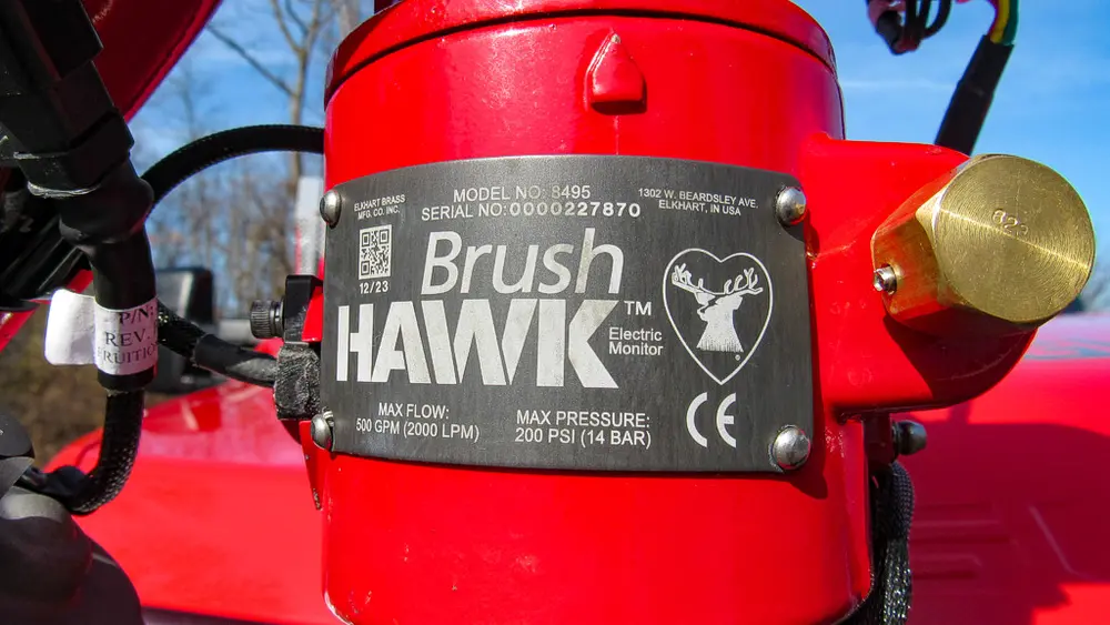 Exterior view of small fire truck showing cab, body compartments, and wheel/tire area.