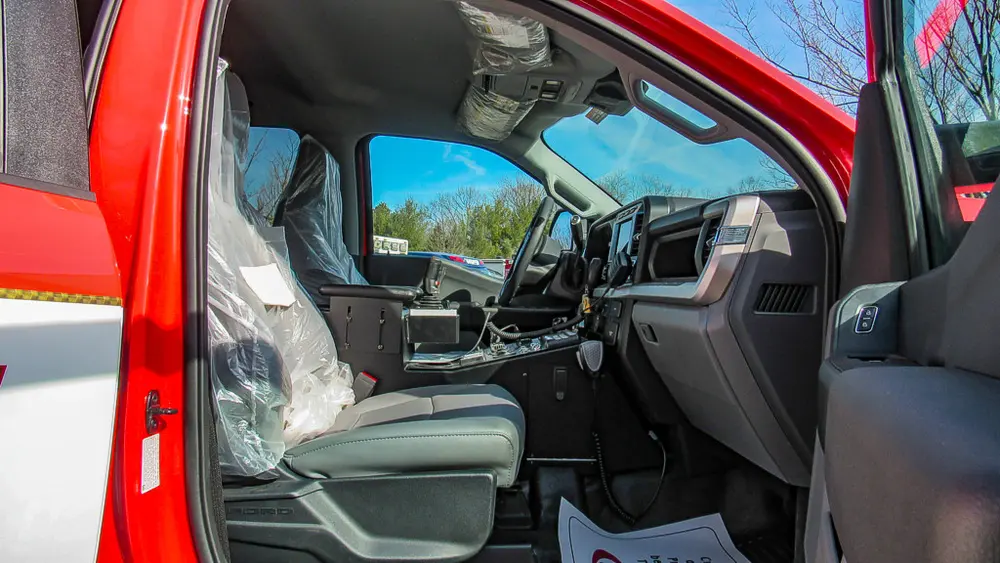 Exterior view of small fire truck showing cab, body compartments, and wheel/tire area.