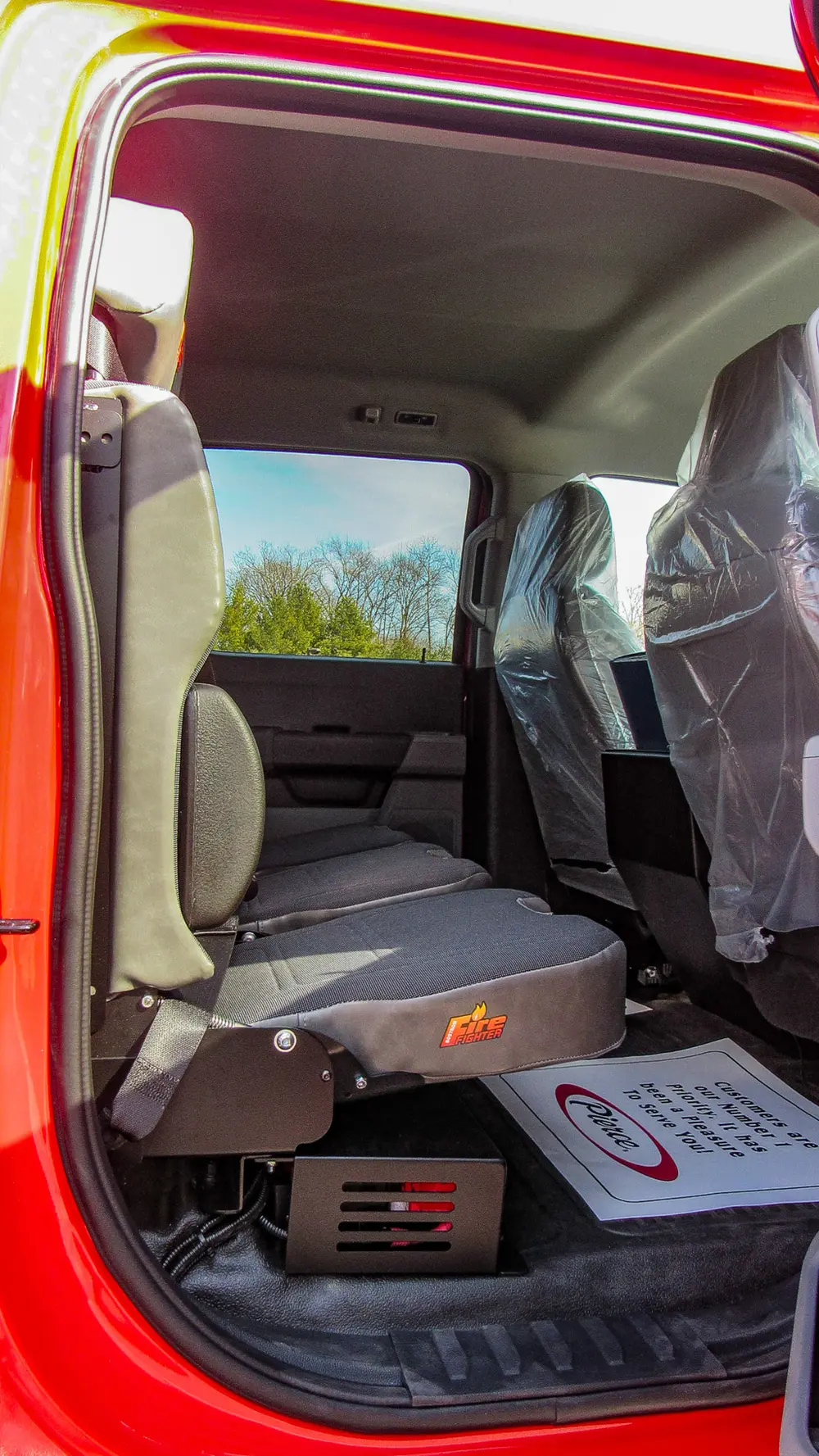 Exterior view of small fire truck showing cab, body compartments, and wheel/tire area.