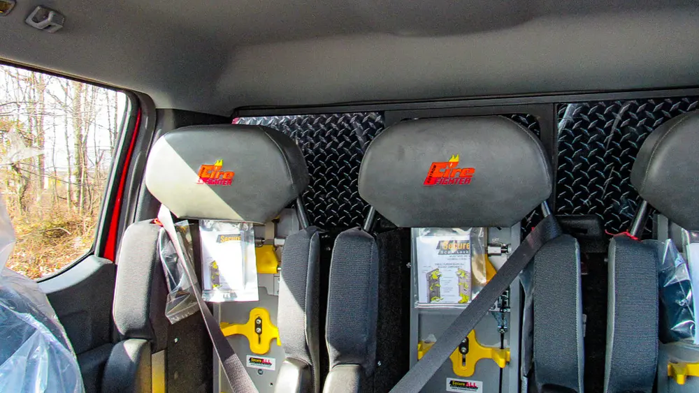 Exterior view of small fire truck showing cab, body compartments, and wheel/tire area.