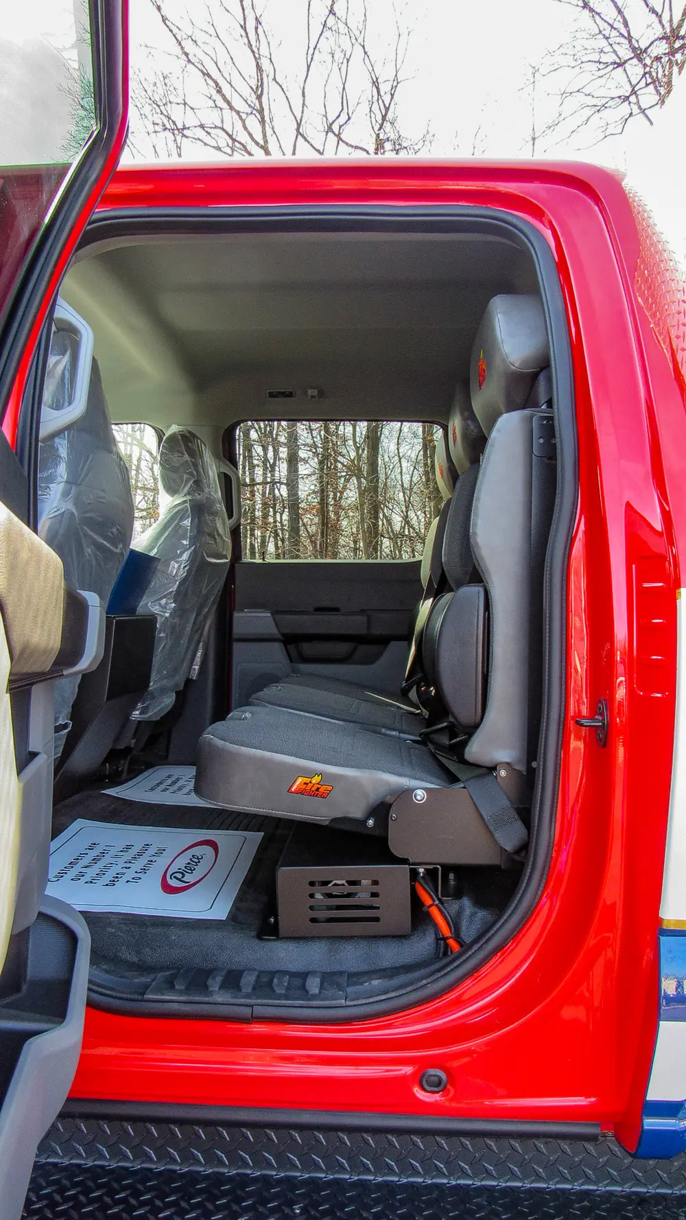 Exterior view of small fire truck showing cab, body compartments, and wheel/tire area.