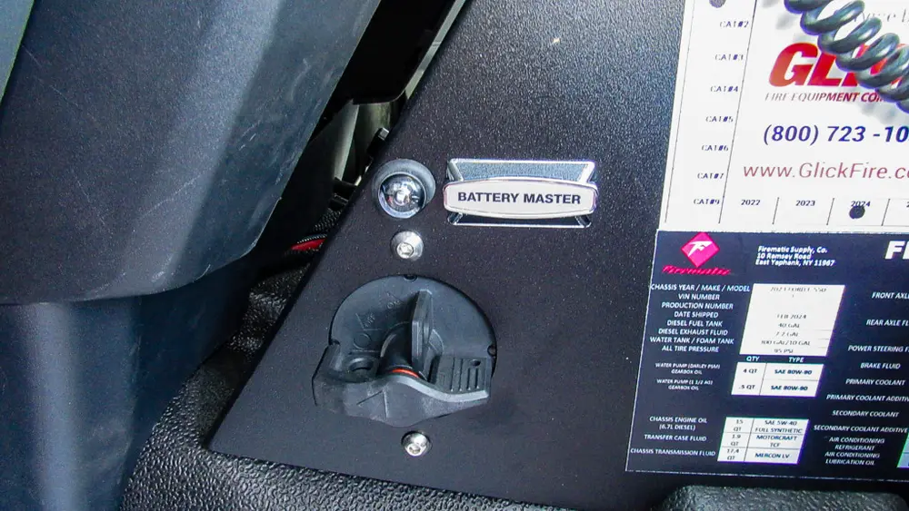 Exterior view of small fire truck showing cab, body compartments, and wheel/tire area.