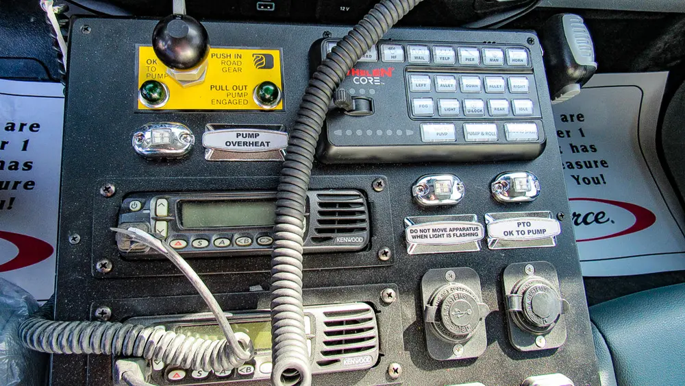 Exterior view of small fire truck showing cab, body compartments, and wheel/tire area.